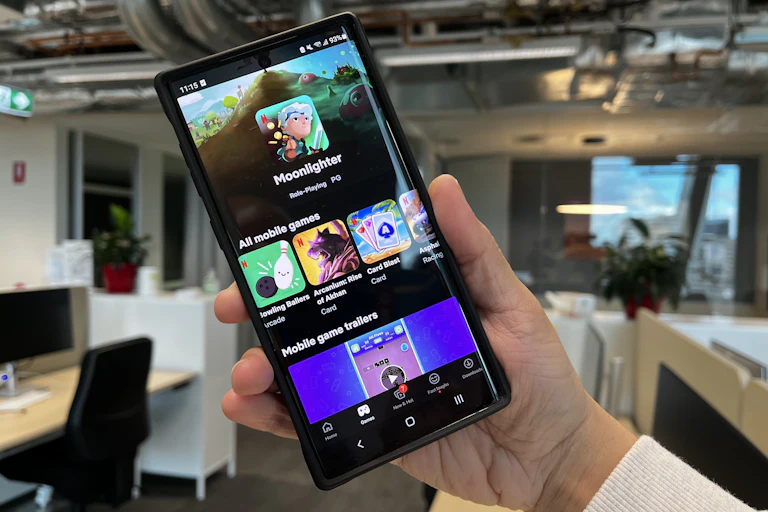 A phone with Netflix's game screen is held up in an office