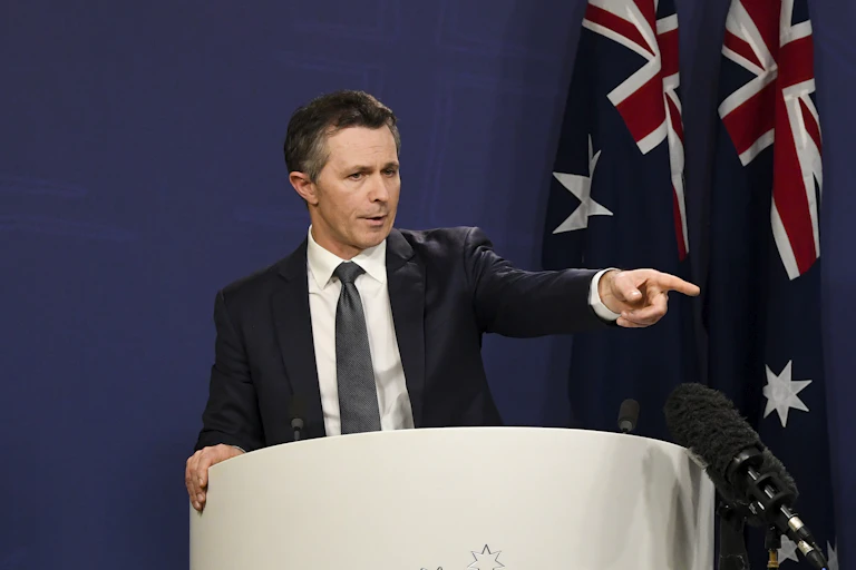 Man in suit at podium points to a questioner