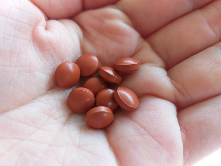 hand with reddish brown pills