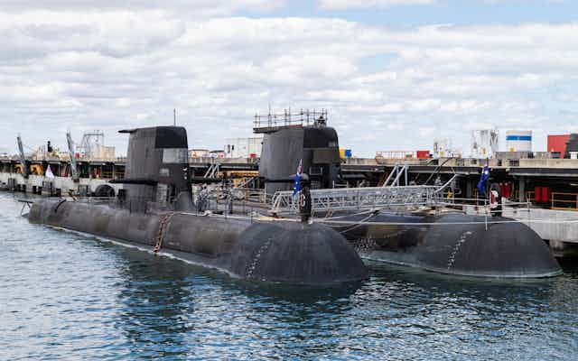 Two Collins class submarines parked in the water