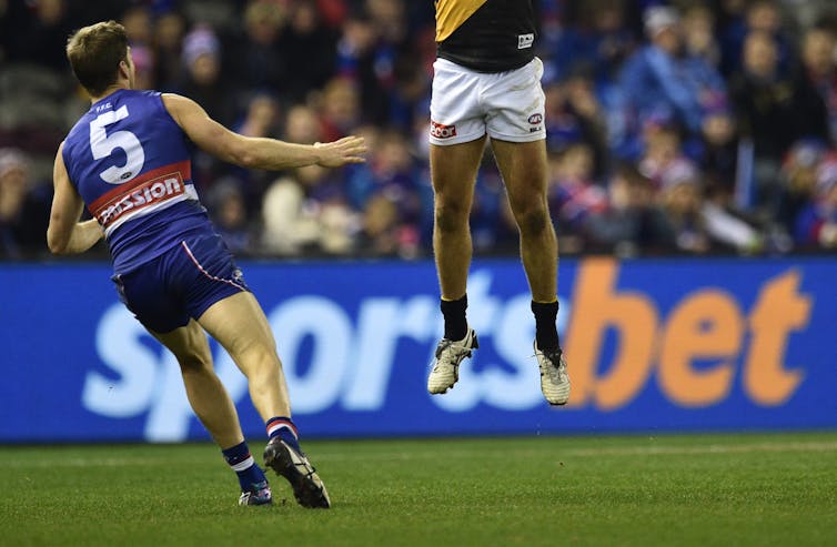 A huge Sportsbet advertisement is behind two AFL players