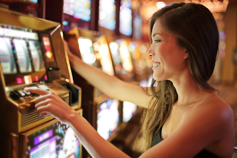 A close up shot of a young woman gambling at a slot machine