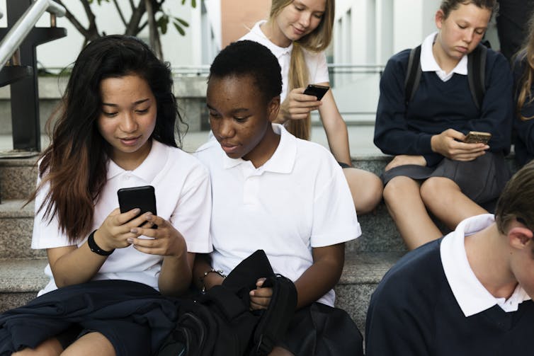 Group of teens in uniform looking at phones