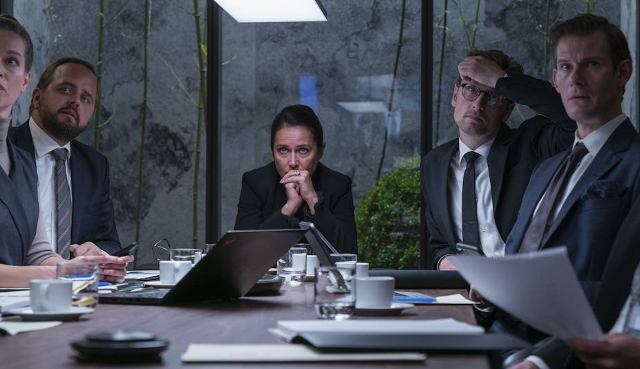 A scene from Borgen showing Nyborg at the head of a table, surrounded by advisers, looking concerned with her hands clasped in front of her mouth