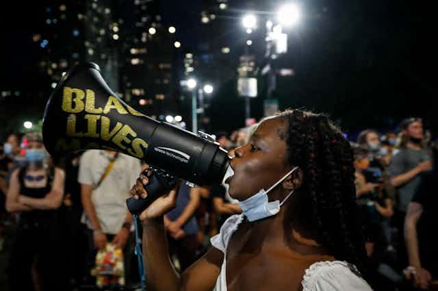 Protestor speaks in a megaphone with Black Lives Matter written on it. 