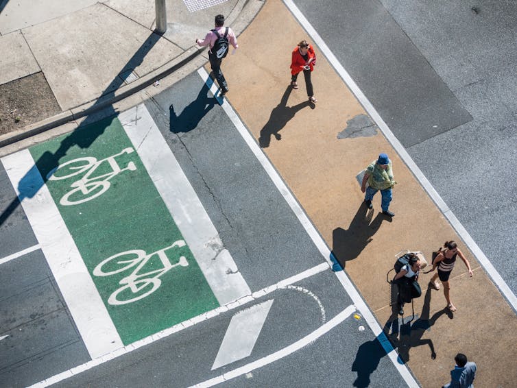 Aerial view of pedestarians crossing roaad and a bike lane next to pedestrian crossing