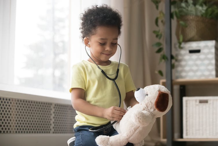 Young boy playing with a stethoscope listens to teddy's chest