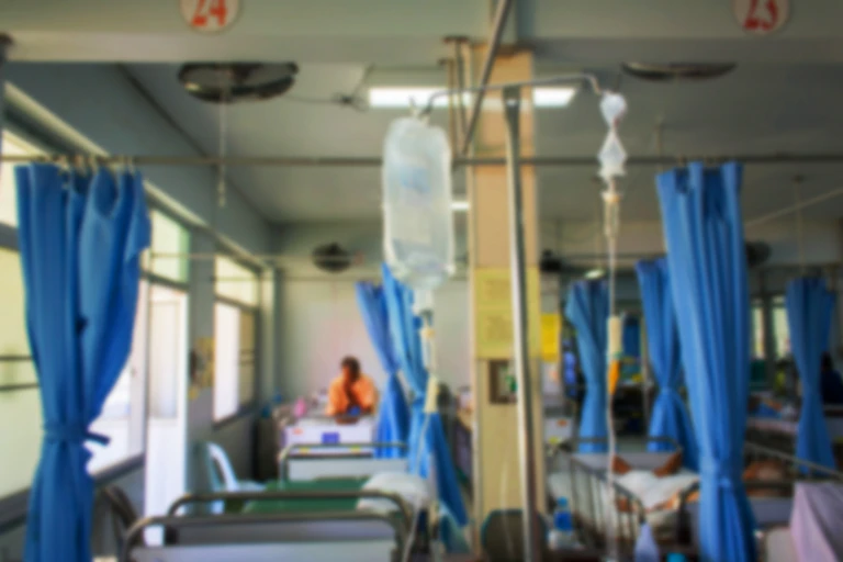 Hospital room with curtains pulled up and a drip.