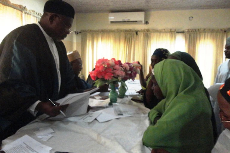 A man standing in front of some women wearing head scarfs