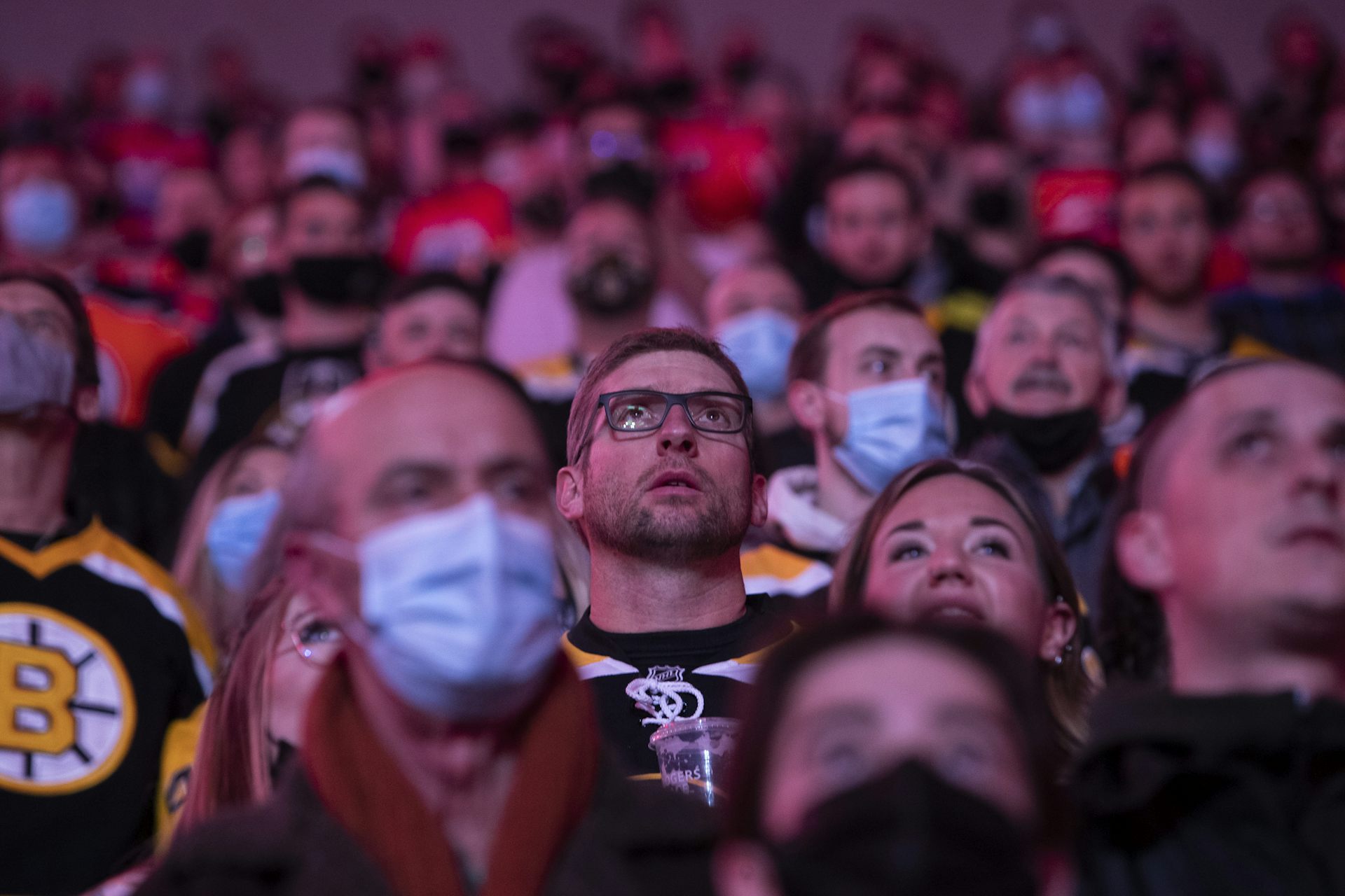 Hockey fans take in a game, some wearing masks and others maskless.