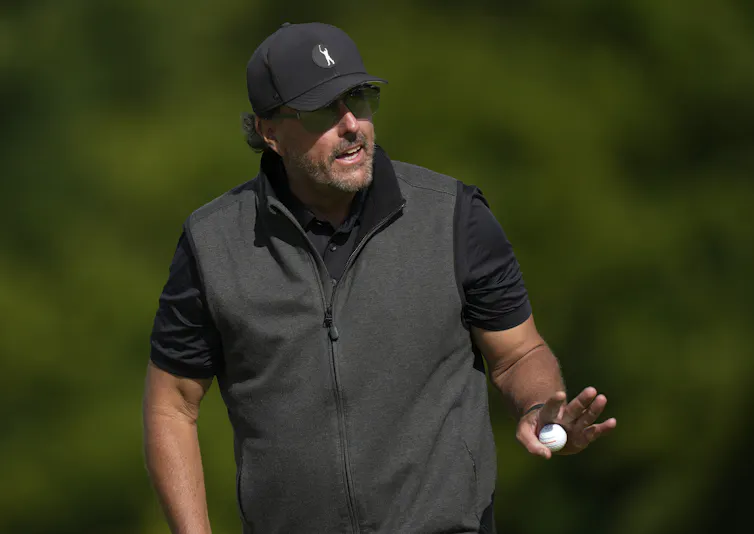 A man waves his hand with a golfball in it