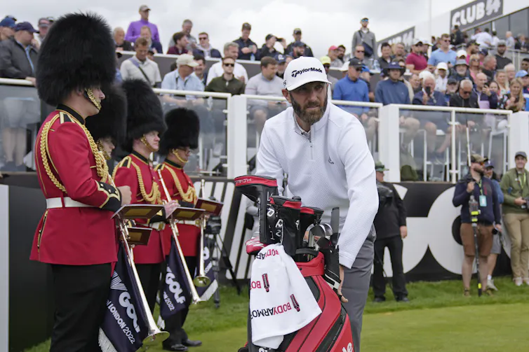 A man puts his golf bag down.