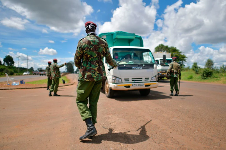 Men in uniform stopping a vehicle on the road.