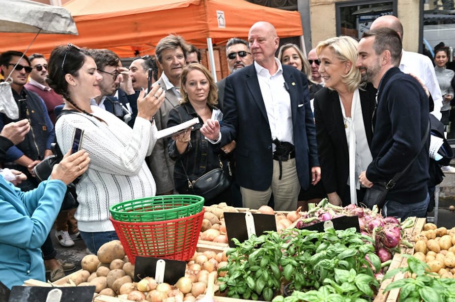 Marine Le Pen sur un marché à Agde dans l'Hérault avec le candidat RN et se fait photographier par les passants.