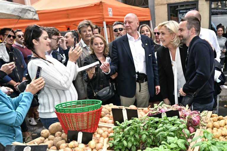Marine Le Pen sur un marché à Agde dans l'Hérault avec le candidat RN et se fait photographier par les passants.