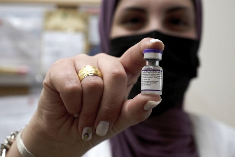 Close up shot of a woman in a hijab holding a vaccine vial