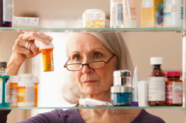 Person looking at pill bottles in medicine cabinet
