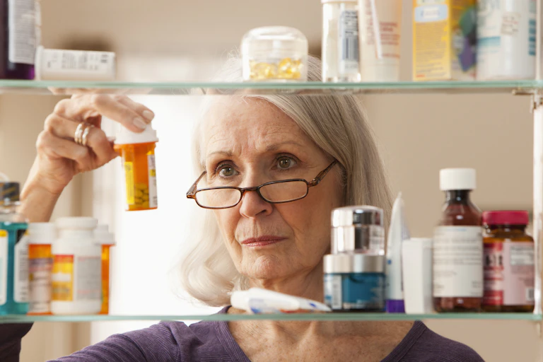 Person looking at pill bottles in medicine cabinet