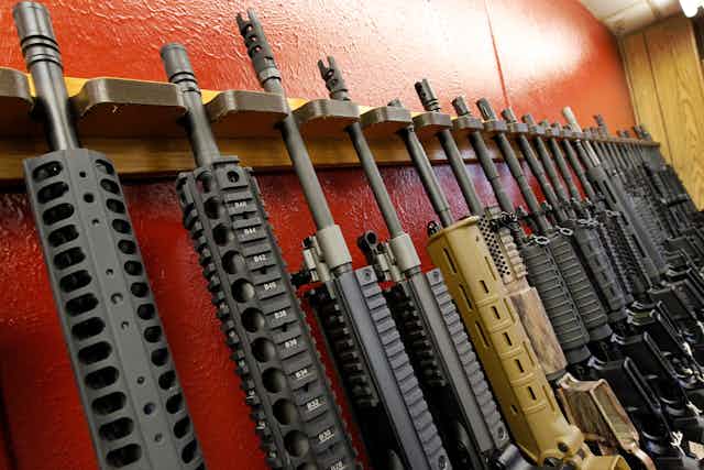 A row of firearms sits in a wooden rack
