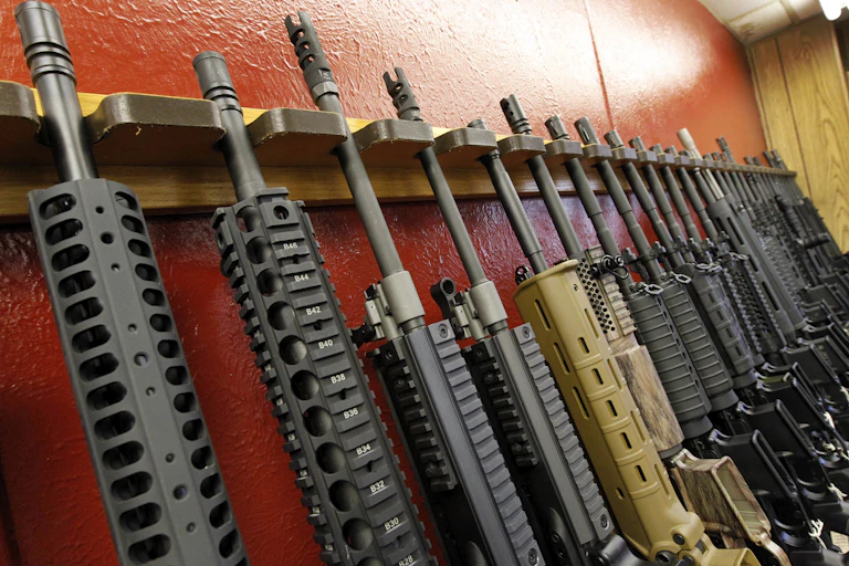 A row of firearms sits in a wooden rack