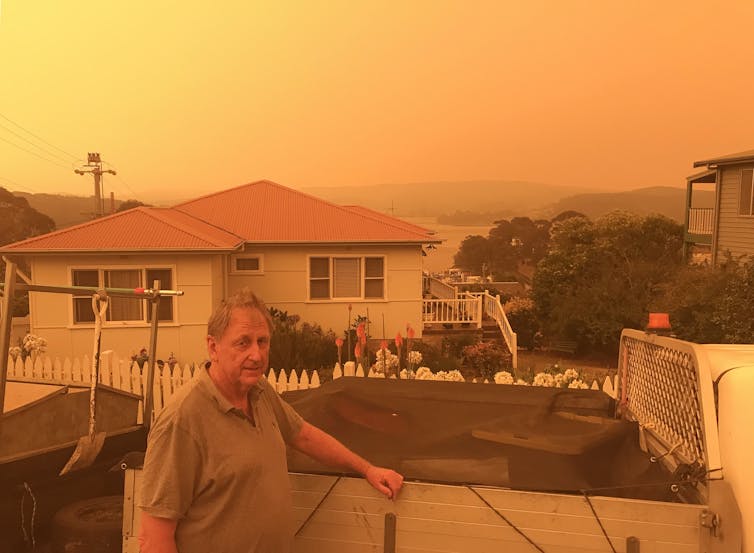man stands in front of house with orange sky