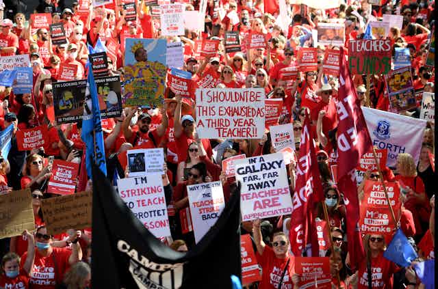striking teachers march and wave protest banners