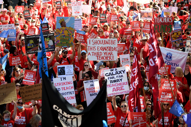 striking teachers march and wave protest banners