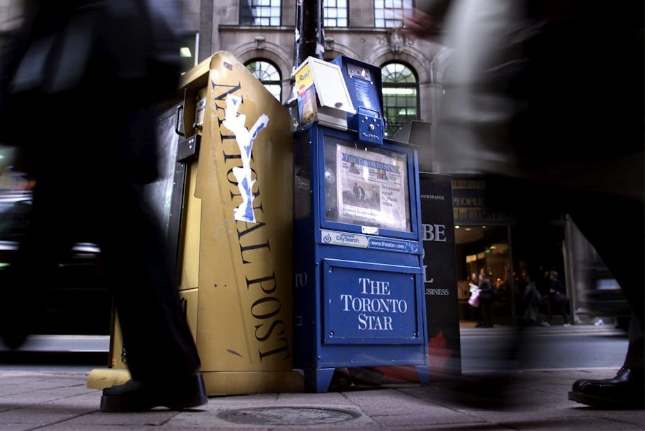 People walk by two newspaper boxes in downtown Toronto