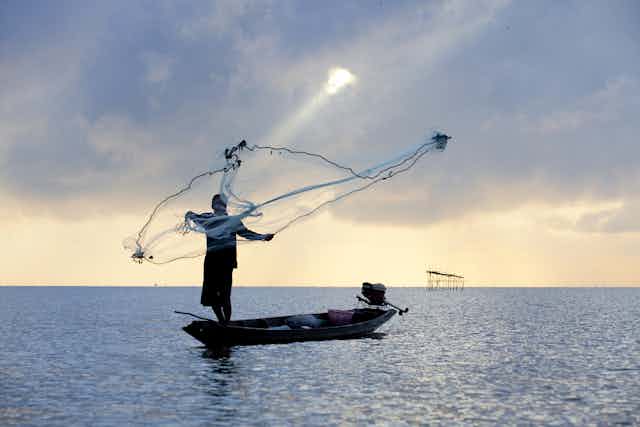 Man casting fishing net into the ocean.