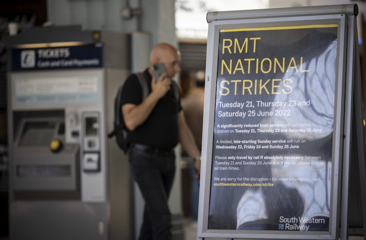 Man on the phone walks behind RMT national strike sign