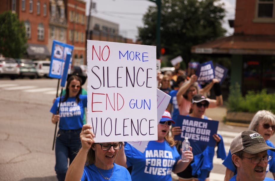 Women and a man in blue 'March for Our Lives' t-shirts hold up a banner saying 'No more silence. End gun violence."
