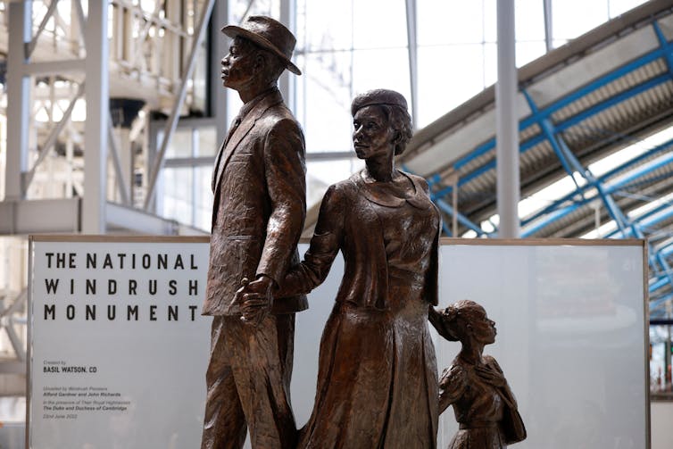 A bronze statue depicts a black man looking at the sky while holding hands with his wife and child.