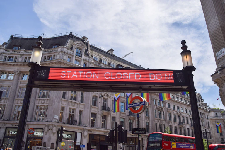 A red sign above the entrance to an Underground station in a big city.