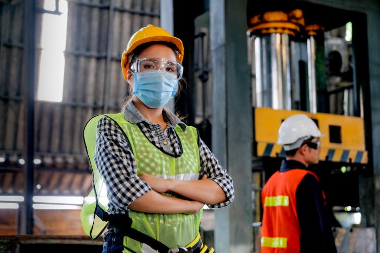 A factory worker in protective gear looks at the camera.