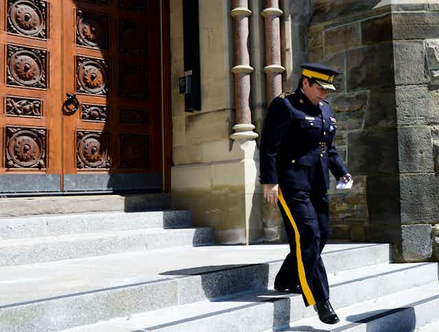 A woman in an RCMP uniform walks down stairs