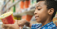A boy is reading a label in a supermarket.