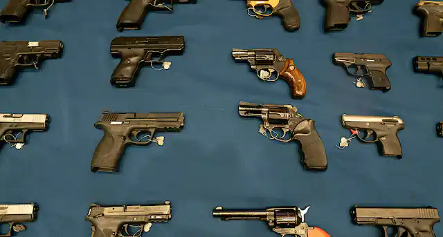 A variety of handguns are seen on a table.