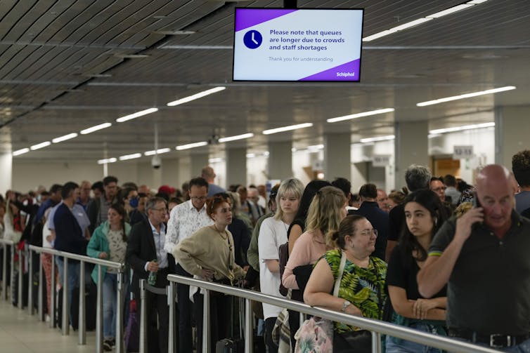 A line of people waiting behind a railing in an airport