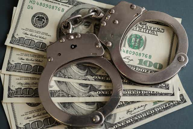 A pair of handcuffs on top of four hundred dollar bills