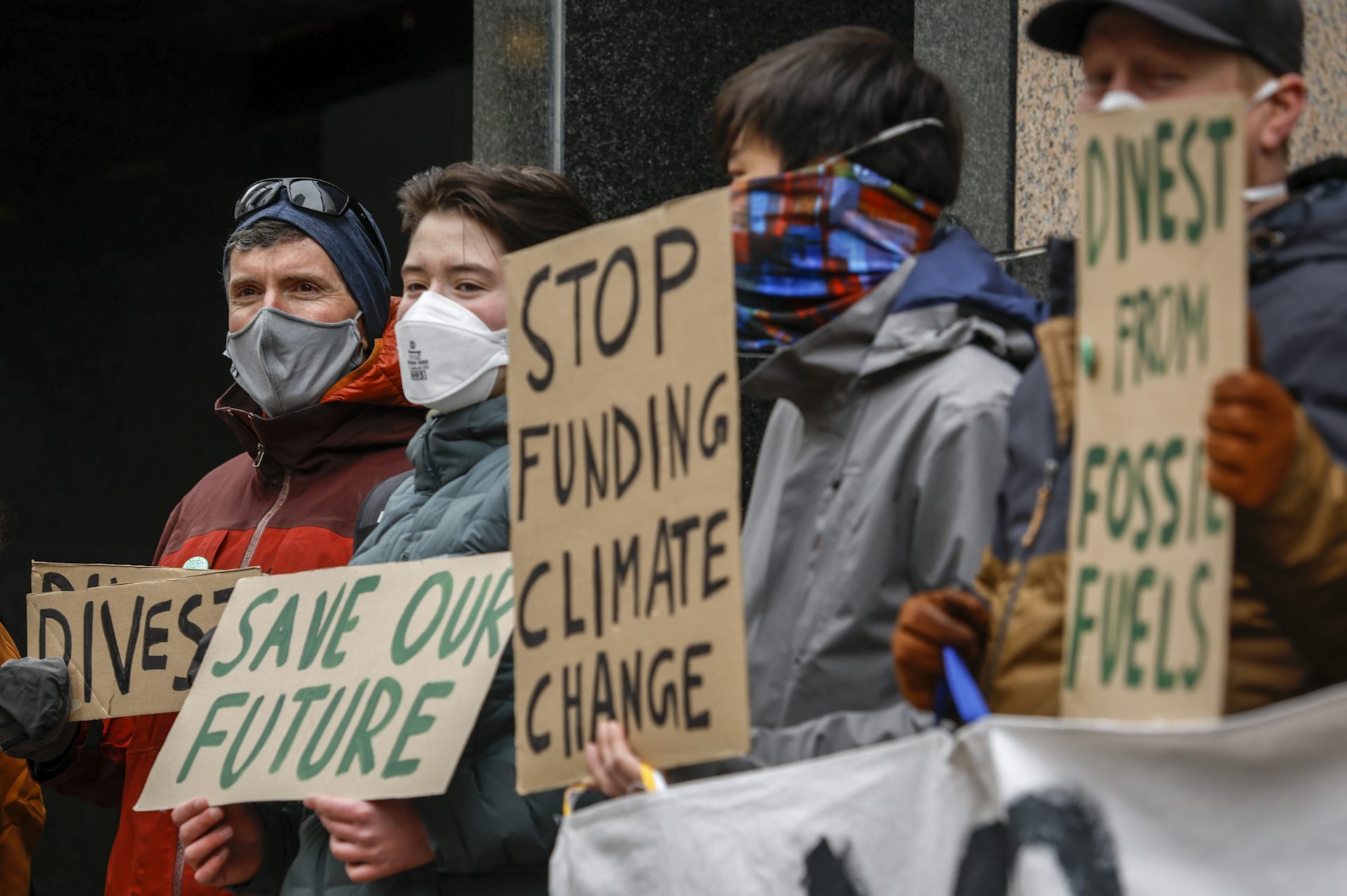 Climate activists holding up a variety of signs demonstrate  in downtown Calgary