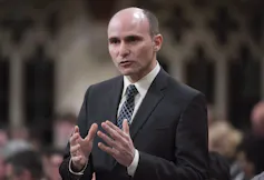 A man in a suit gesturing with his hands as he speaks