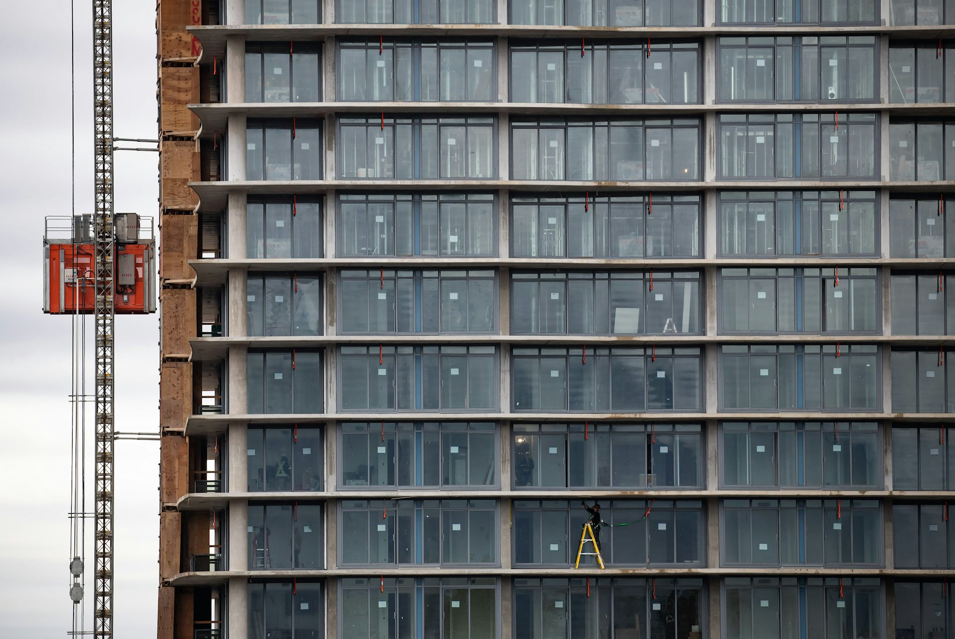 A construction worker standing on the balcony of a building under construction
