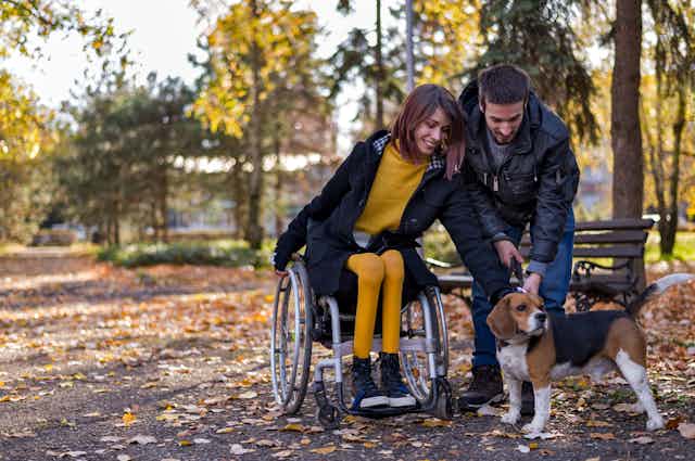 young couple with dog outside, woman is in wheelchair
