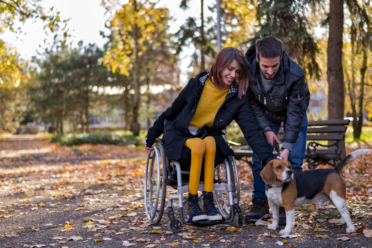 young couple with dog outside, woman is in wheelchair