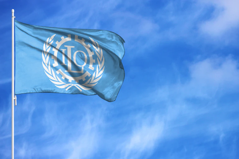 Blue ILO flag on a flagpole, blue sky background