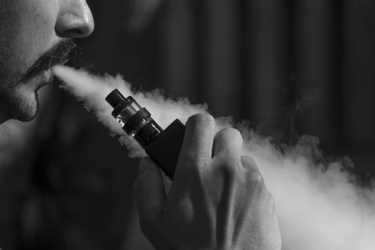 Seorang laki-laki menggunakan rokok elektrik.