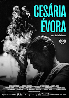 A film poster shows a woman in silhouette, her hand holding a cigarette that send smoke into the lights behind her.