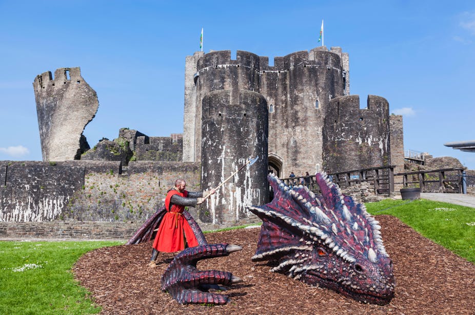 A knight attacks a dragon outside a castle. 