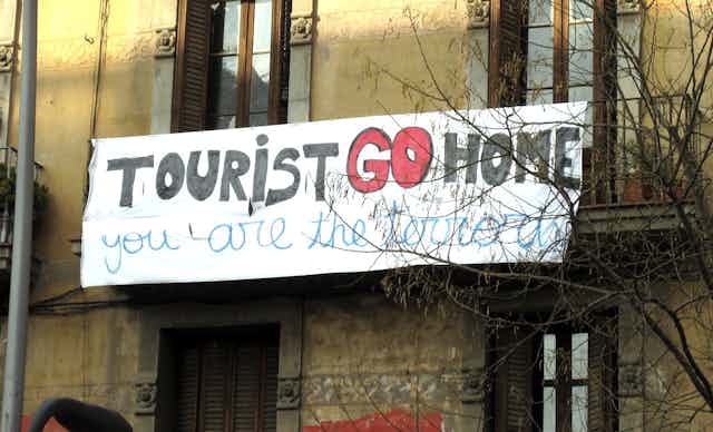 Banderole affichée sur un immeuble de Barcelone, en Espagne, sur laquelle on peut lire « touriste, rentre chez toi, c'est toi le terroriste ». 