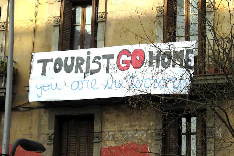 Banderole affichée sur un immeuble de Barcelone, en Espagne, sur laquelle on peut lire « touriste, rentre chez toi, c'est toi le terroriste ».